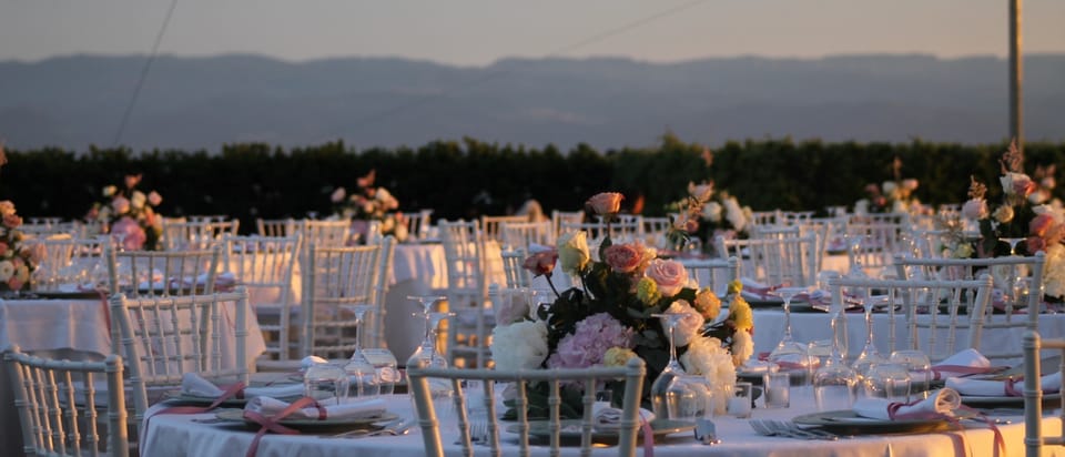 Tavoli con fiori sotto le luci a filo sulla terrazza di Villa Hera.