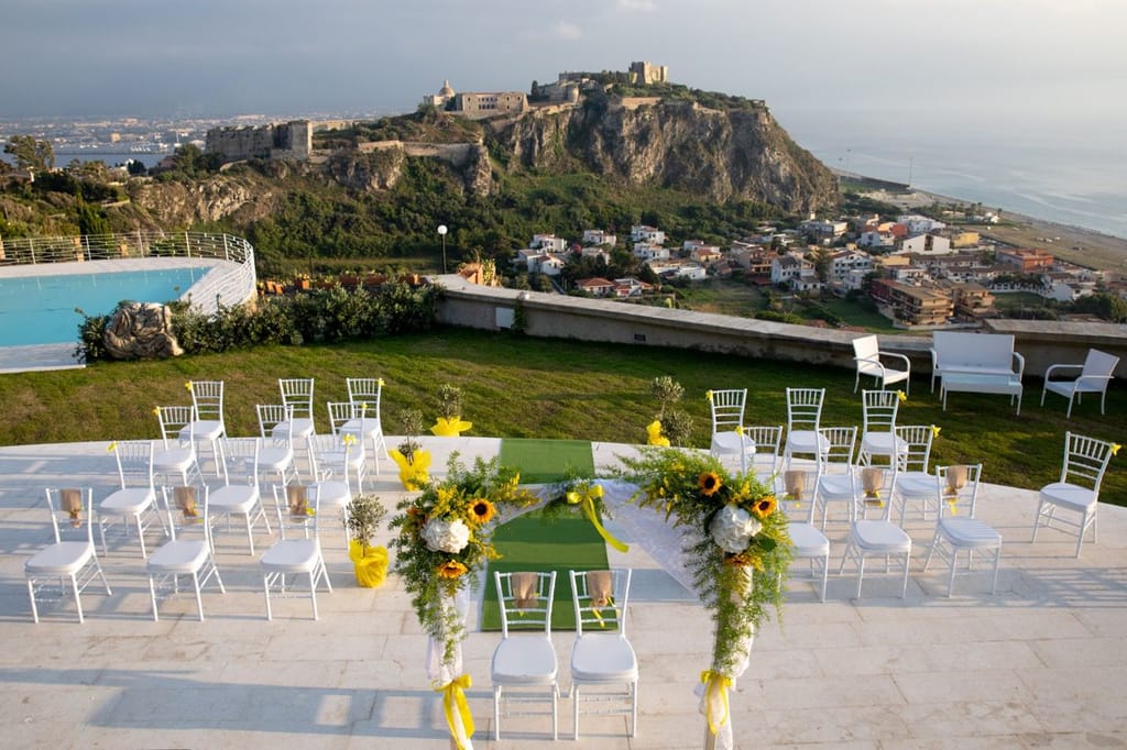 Cerimonia con girasoli e sedie bianche davanti al Castello di Milazzo.