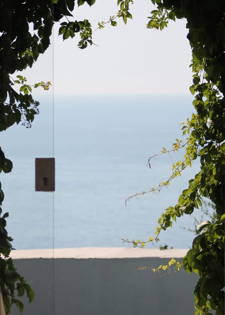 Porta ad arco di Villa Hera: tra i rampicanti si apre la vista sul mare di Capo Milazzo.