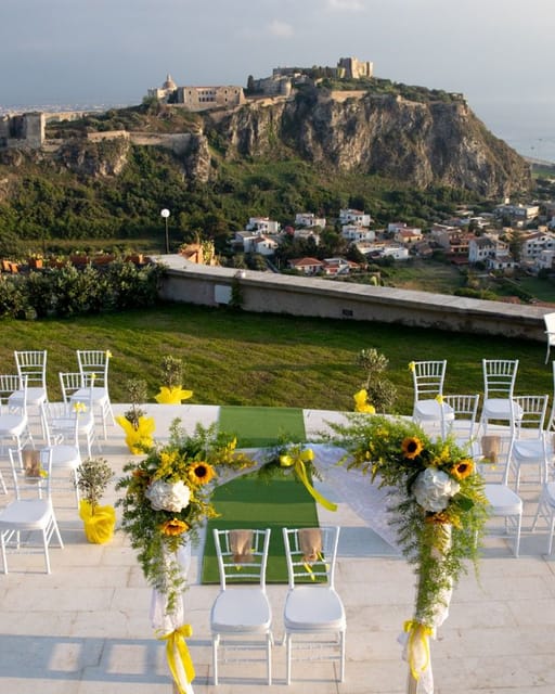 Cerimonia con girasoli e sedie bianche davanti al Castello di Milazzo.