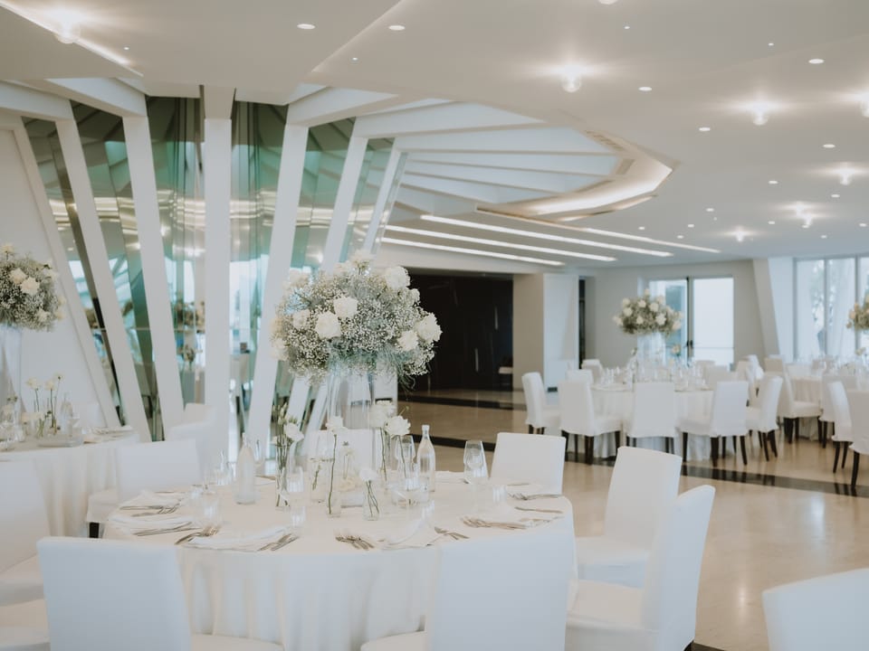 Sala Panoramica di Villa Hera allestita in bianco, con centrotavola alti di rose e gypsophila.