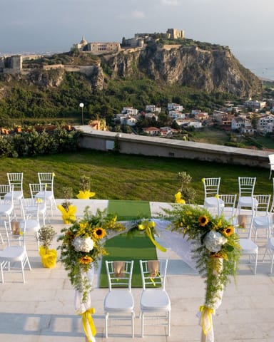 Cerimonia con girasoli e sedie bianche davanti al Castello di Milazzo.