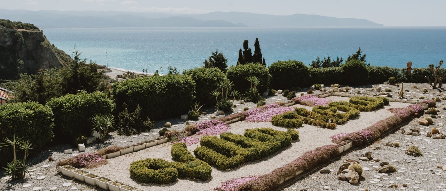 Il nome Villa Hera disegnato nella siepe del giardino, con il mare sullo sfondo.
