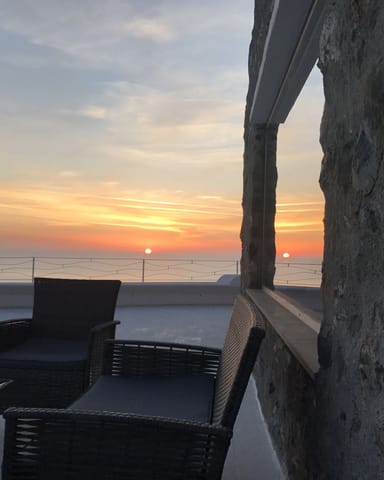 Tramonto sul mare visto da una terrazza in pietra di Villa Hera, con le sedute rivolte all’orizzonte.